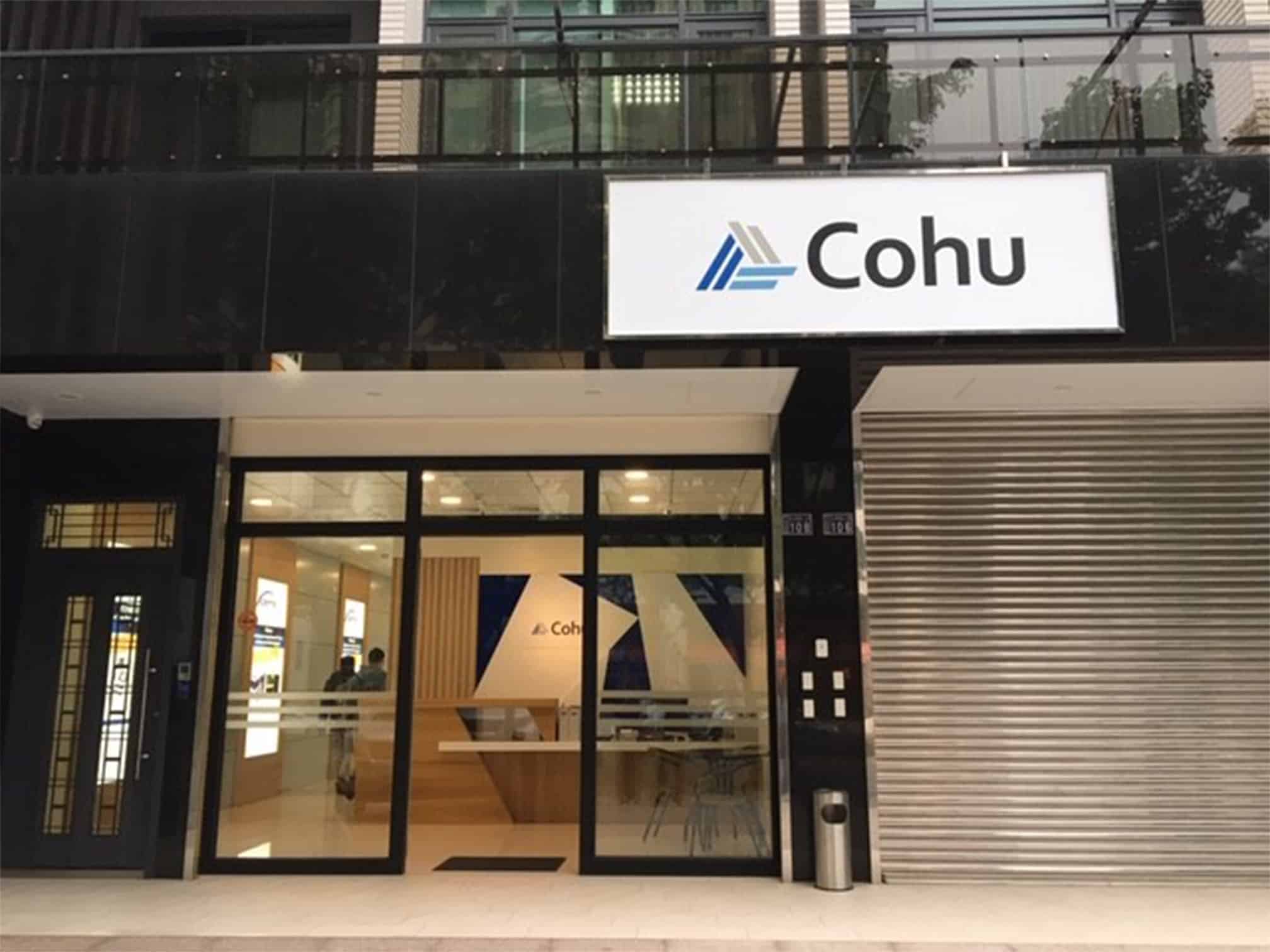 The outside of an office building with the words Cohu above the doorway. The entryway is glass and a reception desk can be seen from the outside.