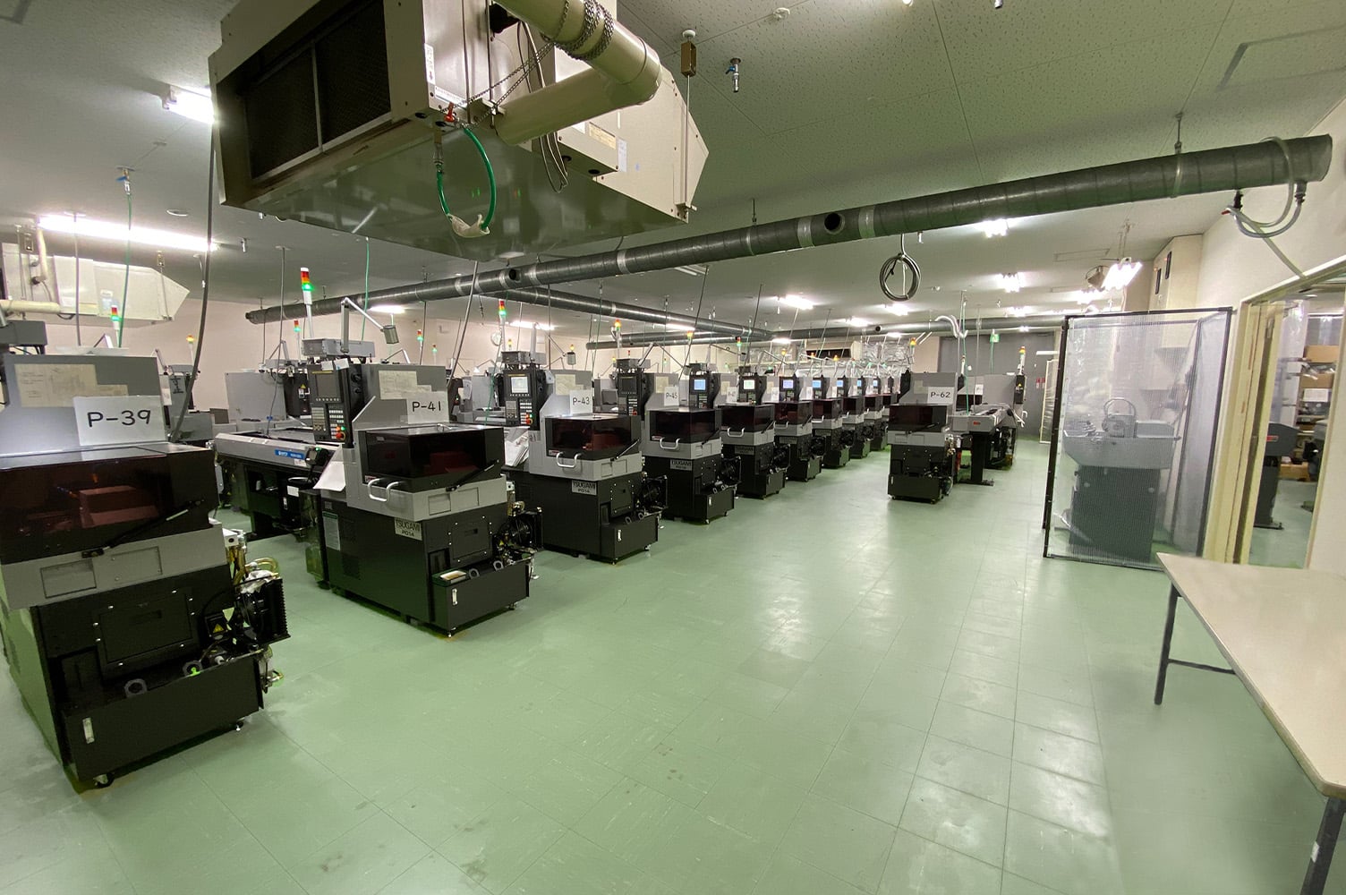 A production floor with light green floors and about 12 machines.